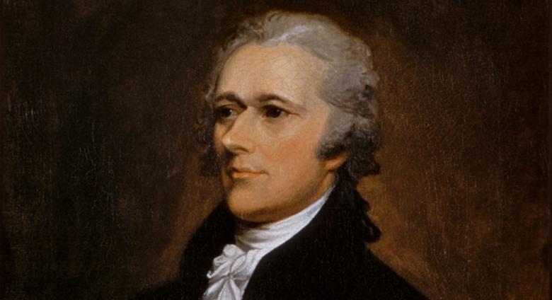 Alexander Hamilton Sits in a dark suit and looks off to the left. 