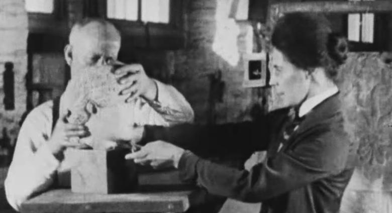 Two met workers from the 1920s adjust the head of a sculpture