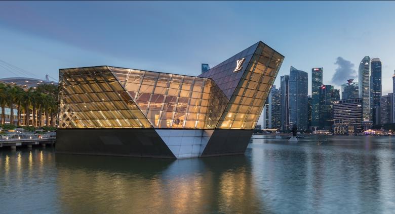 Illuminated polyhedral building Louis Vuitton over the water at Marina Bay in the evening, with skyscrapers of the Central Business District in the background, Singapore. License