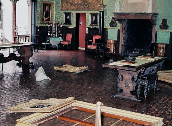 Still from This is a Robbery: The World's Biggest Art Heist. Snapshot of the crime scene in the Dutch Room at the Isabella Stewart Gardner Museum. Empty frames, crime scene tape and what appears to be trash litter the floor.